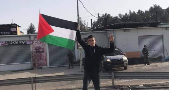 Un jeune palestinien lève le drapeau de la Palestine sur les ruines de son magasin à Ramallah