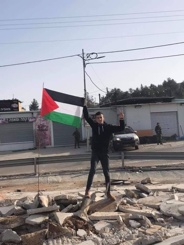 Un jeune palestinien lève le drapeau de la Palestine sur les ruines de son magasin à Ramallah