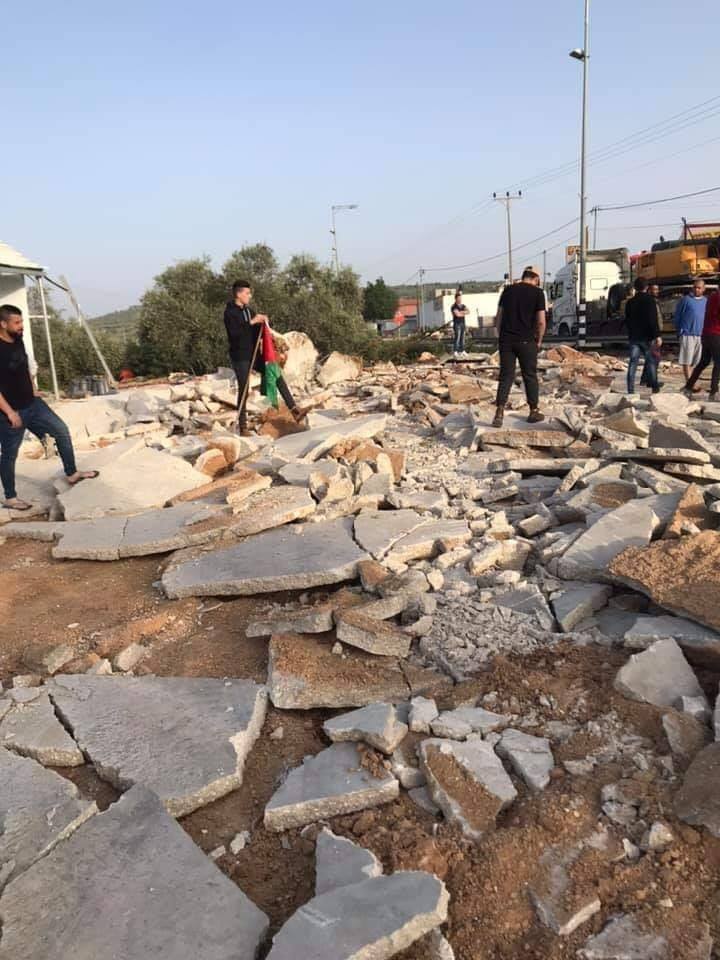 Un jeune palestinien lève le drapeau de la Palestine sur les ruines de son magasin à Ramallah1